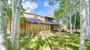 A modern house with a large glass front, surrounded by birch trees. - Dog-friendly Home w/ Hot Tub & Decks in Durango! (Durango)