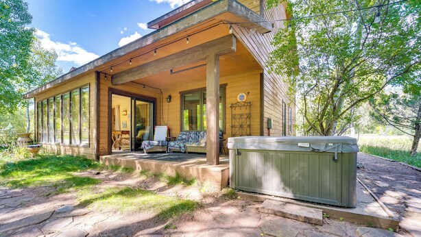 A wooden cabin with a covered porch, stone pathway, and a hot tub. - Dog-friendly Home w/ Hot Tub & Decks in Durango! (Durango)