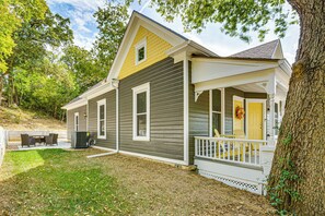 Une maison à deux étages avec un porche, une petite terrasse et une pelouse bien entretenue.