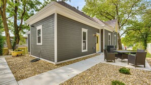 A single-story house with a gray exterior, a yellow front door, and a patio area with outdoor furniture.