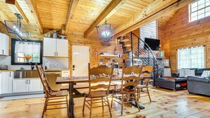 A spacious wooden cabin interior with a dining area, kitchen, and living room.