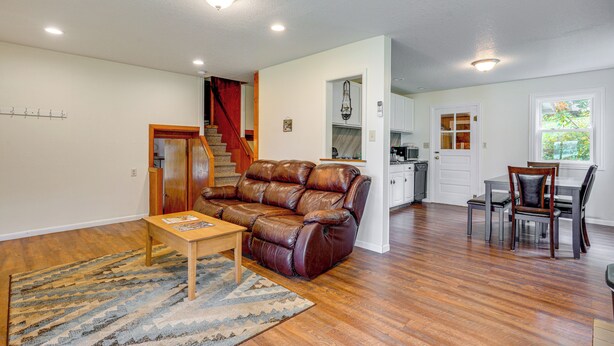 A spacious living room with a leather sofa, wooden coffee table, and a dining area with a table and chairs. - Webster Lake Home w/ Patio ~ 3 Mi to Town! (North Webster)