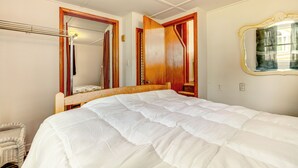 A bedroom with a large bed, wooden headboard, and a mirror with a gold frame. - Webster Lake Home w/ Patio ~ 3 Mi to Town! (North Webster)