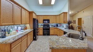 A kitchen with wooden cabinets, granite countertops, a black refrigerator, a stove, and a sink. - Groveland Vacation Rental Near Pine Mountain Lake! (Groveland)