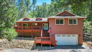 A two-story cabin with a front porch, a garage, and a flag. - Groveland Vacation Rental Near Pine Mountain Lake! (Groveland)