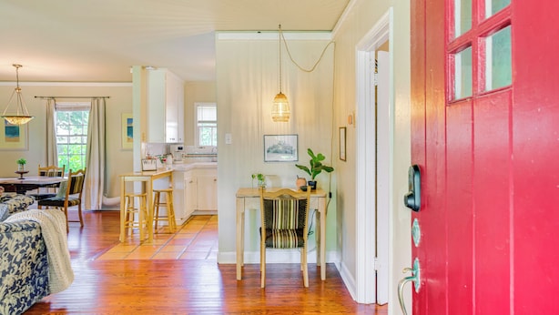 A spacious living room with a wooden floor, a dining area with a table and chairs, and a kitchen area with a countertop and hanging light fixture. - 1939 Bungalow With Original Charm Corpus Christi (Corpus Christi)