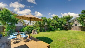 A backyard with a wooden deck, a glass table with chairs, and a large umbrella. - 1939 Bungalow With Original Charm Corpus Christi (Corpus Christi)