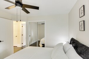 Un dormitorio con cama, ventilador de techo, una puerta y un pasillo.