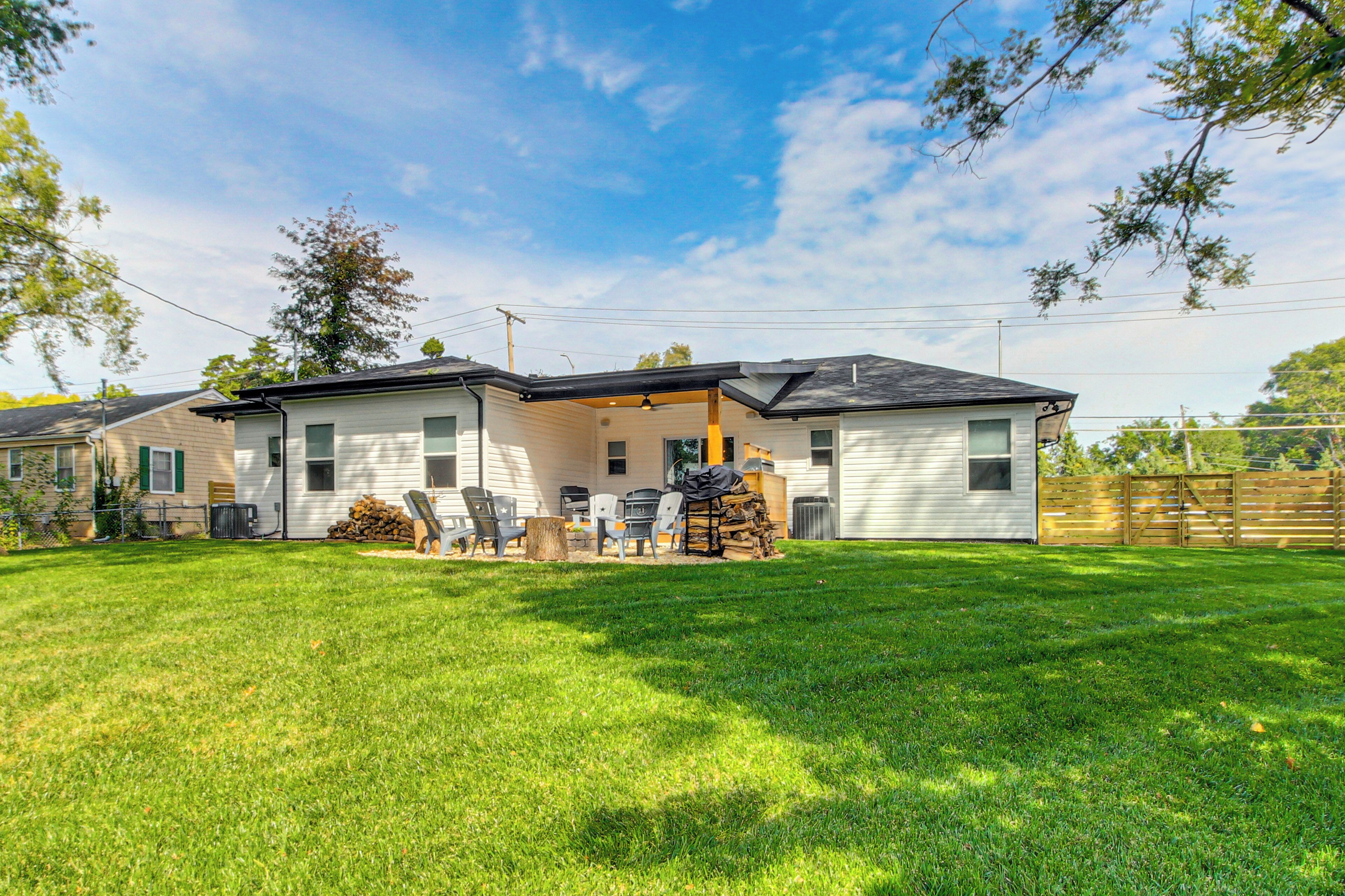 A two-story house with a covered patio, a lawn, and a wooden fence.