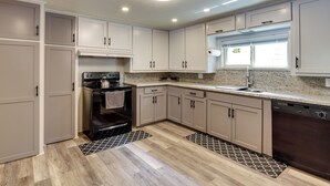 Une cuisine moderne avec des meubles de couleur beige, une cuisinière noire et un lave-vaisselle.