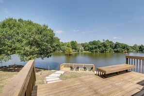 A wooden deck with outdoor seating and a view of a lake surrounded by trees. - Lakefront College Station Home Near Texas A & M! (College Station)