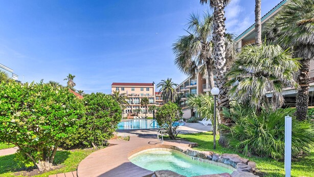 A resort pool area with a wooden deck, a small hot tub, and a view of the hotel buildings in the background. - Walk to Seawall & Beach! Galveston Condo w/ Pool (Galveston)