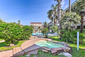 A resort pool area with a wooden deck, a small hot tub, and a view of the hotel buildings in the background. - Walk to Seawall & Beach! Galveston Condo w/ Pool (Galveston)