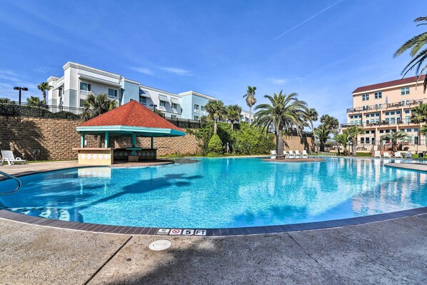 A swimming pool with a no diving sign, a covered seating area, and a view of hotel buildings.