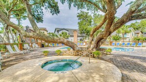 A pool area with lounge chairs and a hot tub, surrounded by trees and buildings. - North Myrtle Beach Home 2 Blocks to Ocean! (North Myrtle Beach)