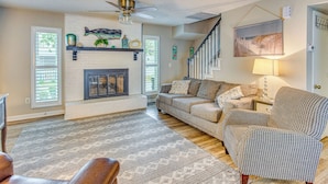 A living room with a fireplace, a sofa, a patterned rug, and a houndstooth armchair. - North Myrtle Beach Home 2 Blocks to Ocean! (North Myrtle Beach)