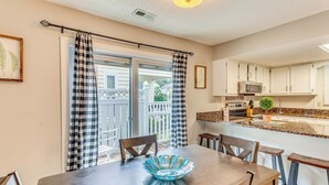 A dining area with a table, chairs, and a blue glass bowl. There is a kitchen area with cabinets and a microwave. - North Myrtle Beach Home 2 Blocks to Ocean! (North Myrtle Beach)