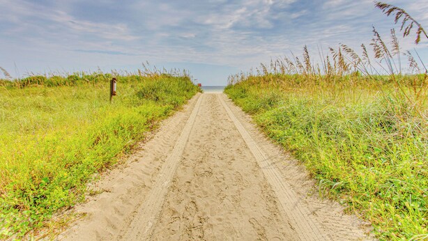 A sandy path leading to the sea with grass on either side. - North Myrtle Beach Home 2 Blocks to Ocean! (North Myrtle Beach)