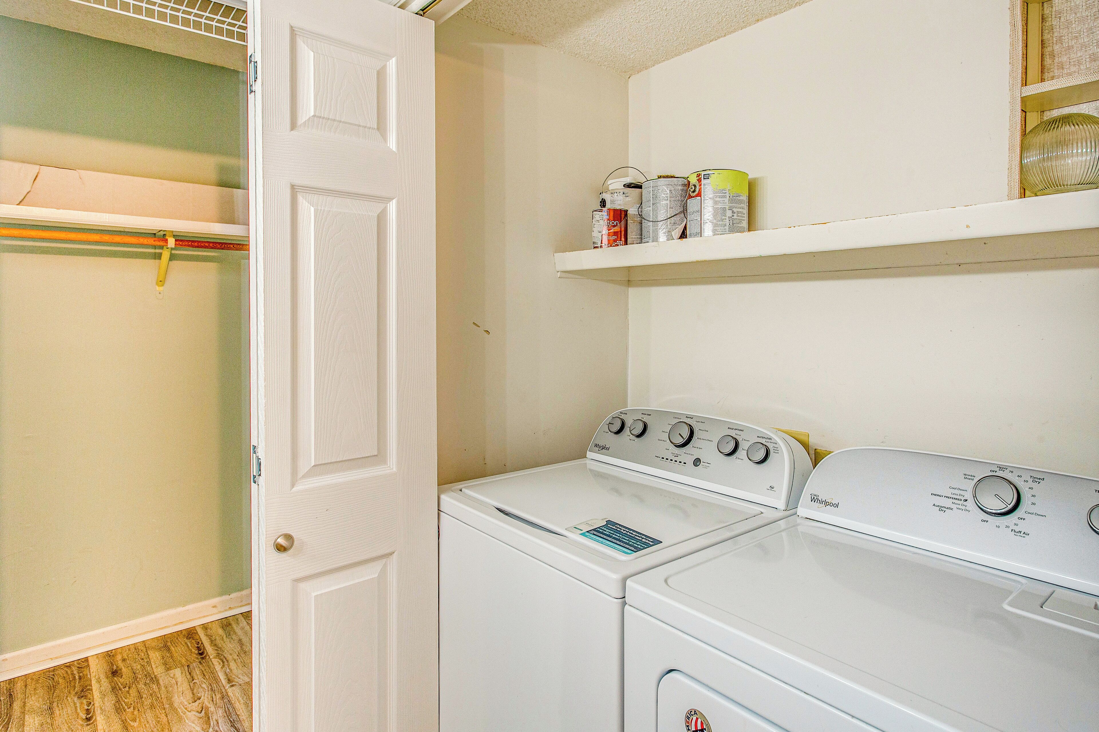 A laundry area with two white Whirlpool washers and dryers, a wooden floor, and a white door.