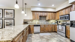 A kitchen with granite countertops, wooden cabinets, stainless steel appliances, and pendant lighting. - Quiet Condo w/ Patio: 3 Mi to Dtwn Branson! (Branson)