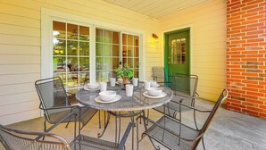 A covered patio with a round metal table and chairs, surrounded by windows and a brick wall. - Quiet Condo w/ Patio: 3 Mi to Dtwn Branson! (Branson)
