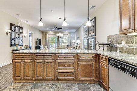 A spacious kitchen with a large island, wooden cabinets, and a dishwasher.
