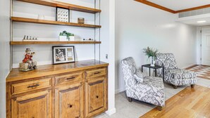 Una sala de estar con un aparador de madera, sillones estampados y piso a cuadros.