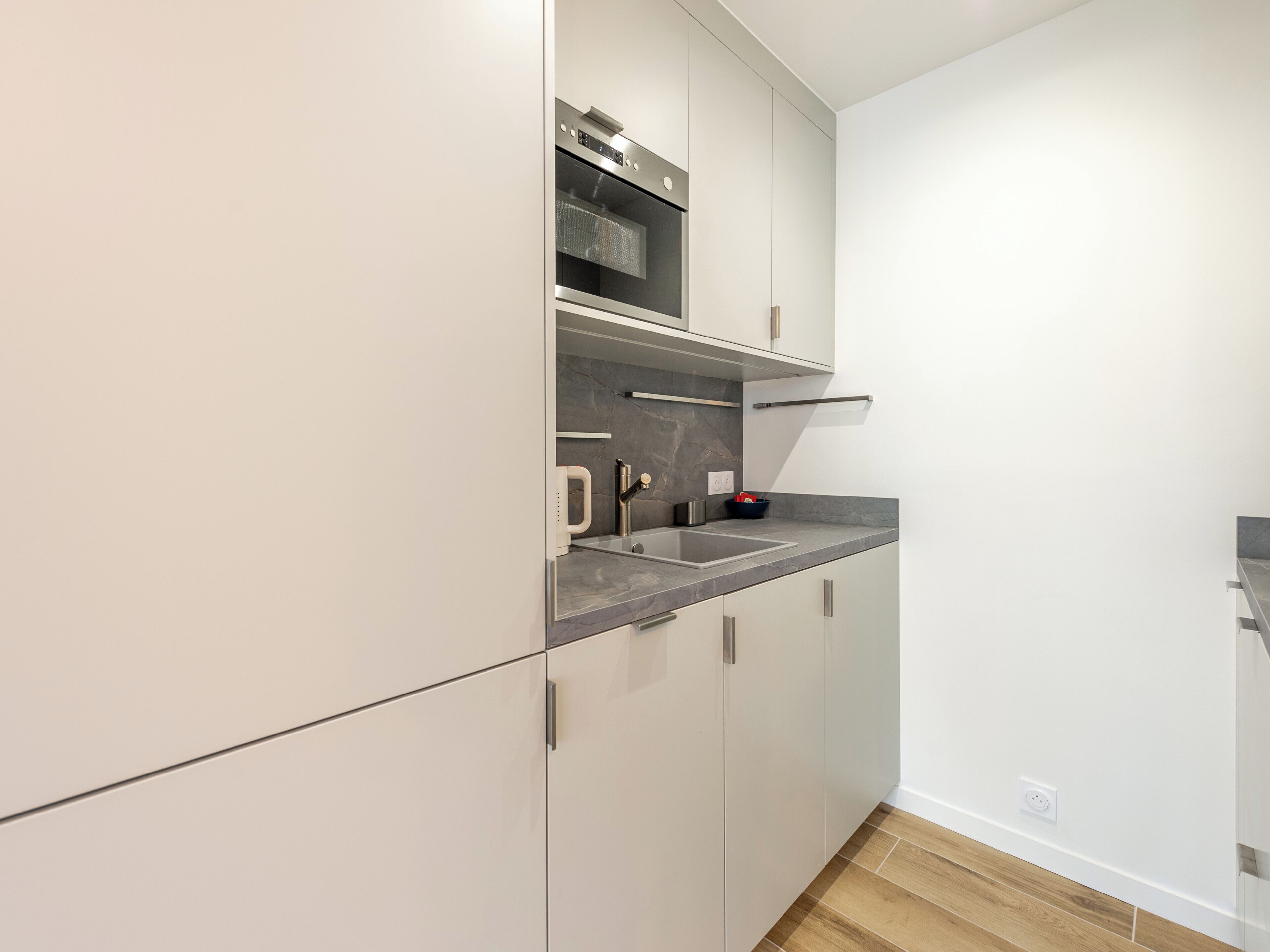 Una cocina moderna con electrodomésticos de acero inoxidable, encimera de mármol y armarios de diseño minimalista.