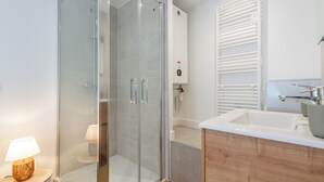 Une salle de bain moderne avec une douche à parois de verre, un lavabo blanc et un meuble-lavabo en bois.