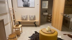 A room with a wooden bench, a wall-mounted picture of a bull, a bathroom with a sink and shelves, and a cowhide rug. - Alpine Myth (Sankt Anton am Arlberg)