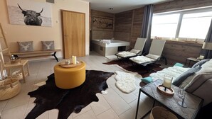 A modern living room with a large black and white cowhide rug, a wooden bench, a sofa, and a dining table with chairs. - Alpine Myth (Sankt Anton am Arlberg)