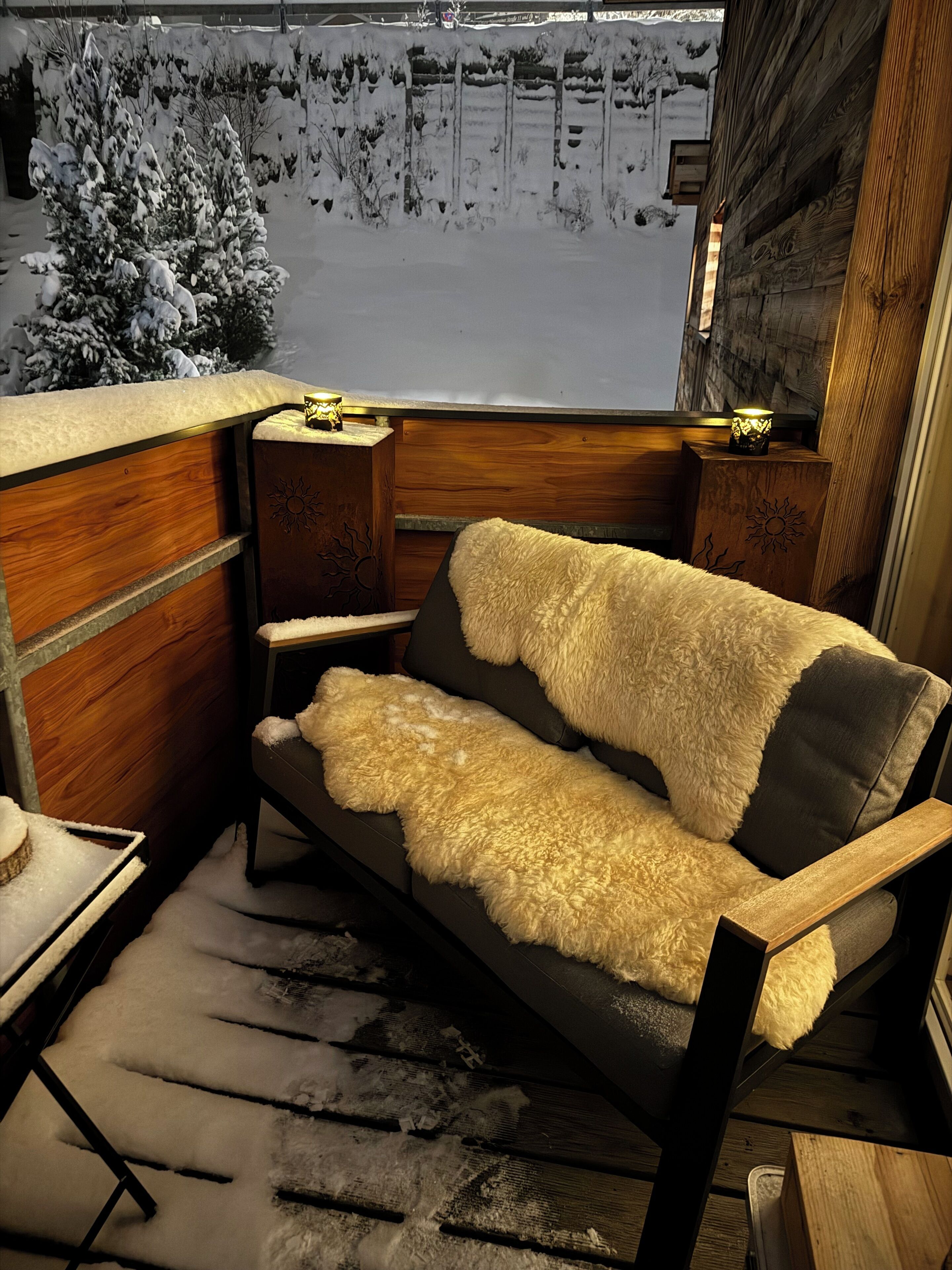 A cozy corner with a wooden bench, a fluffy white throw, and a small table with a lamp.