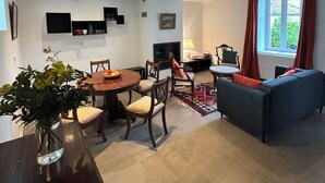 Una sala de estar moderna con un sofá, una mesa de comedor y sillas. Hay una chimenea y un televisor montado en la pared.