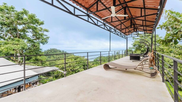 A covered outdoor area with a concrete floor, a ceiling fan, and a view of the surrounding greenery. - Ronny's Flat Manuel Antonio (Quepos)