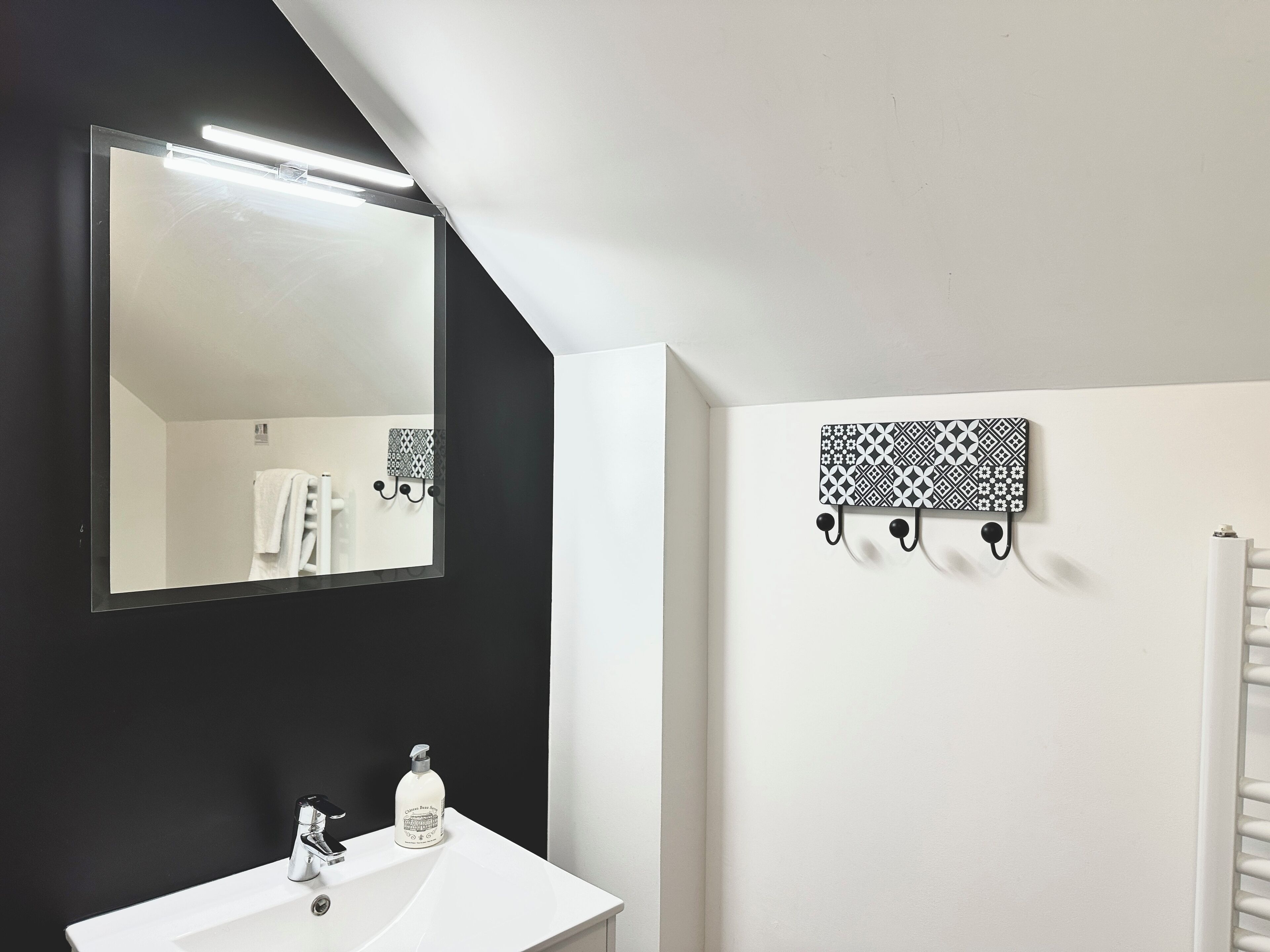 A bathroom with a white sink, a large mirror, and a towel rack.