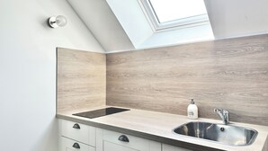 A modern kitchen with a skylight, a stainless steel sink, and light wood cabinetry. - Le Patio de Loiseau  (Le Mans)