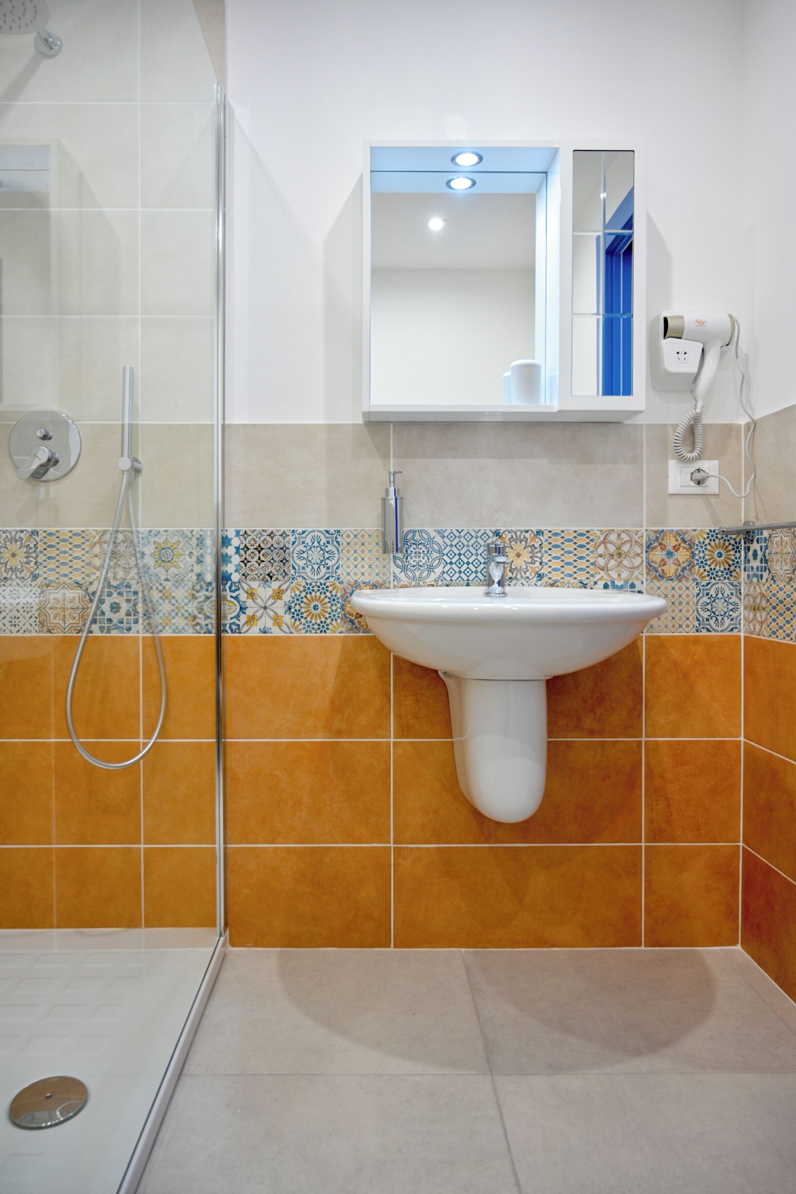 A bathroom with a glass shower enclosure, a white sink, and a mirror above it.