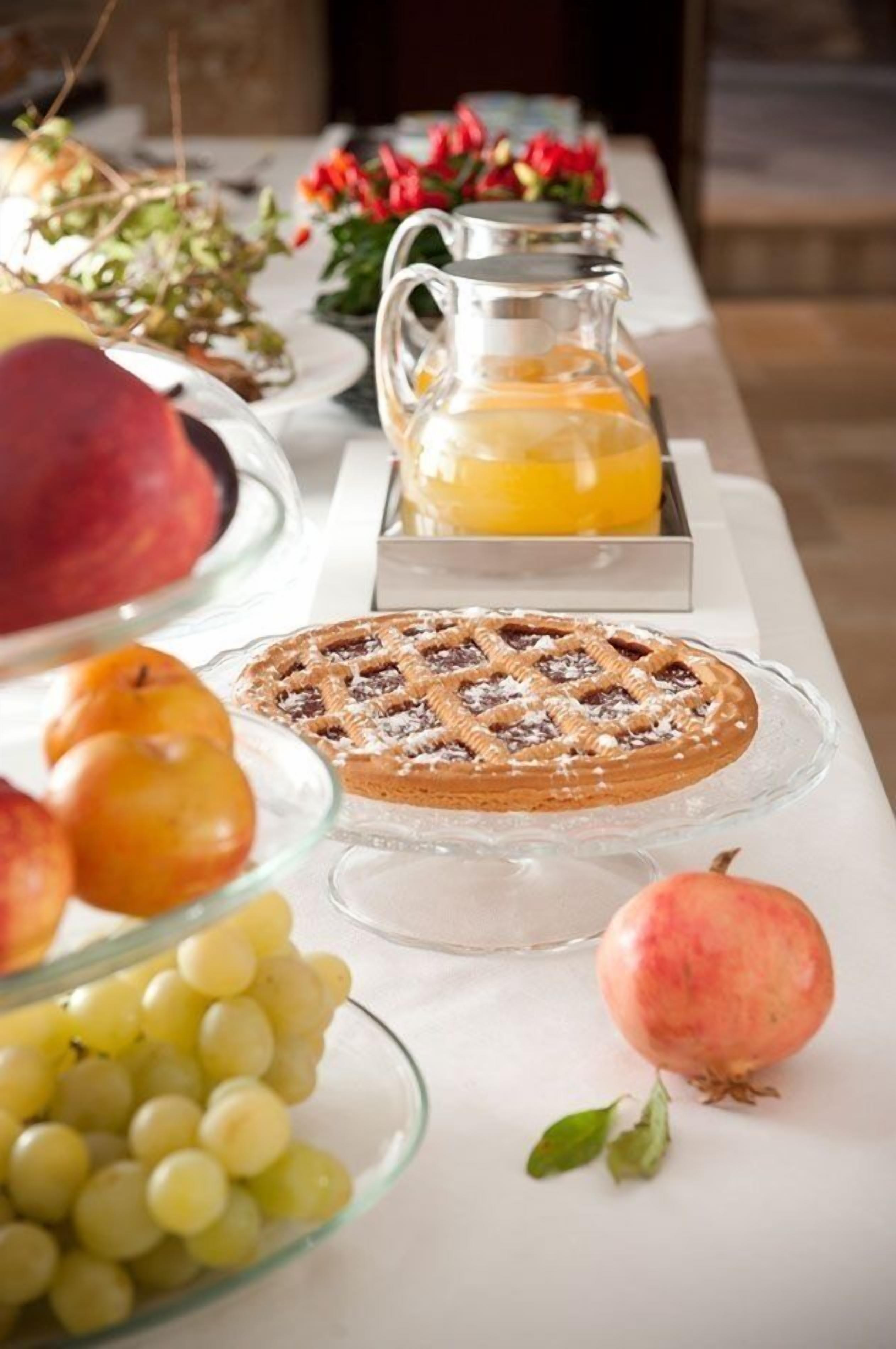 A breakfast buffet with a variety of fruits, a pie, and a pitcher of orange juice.