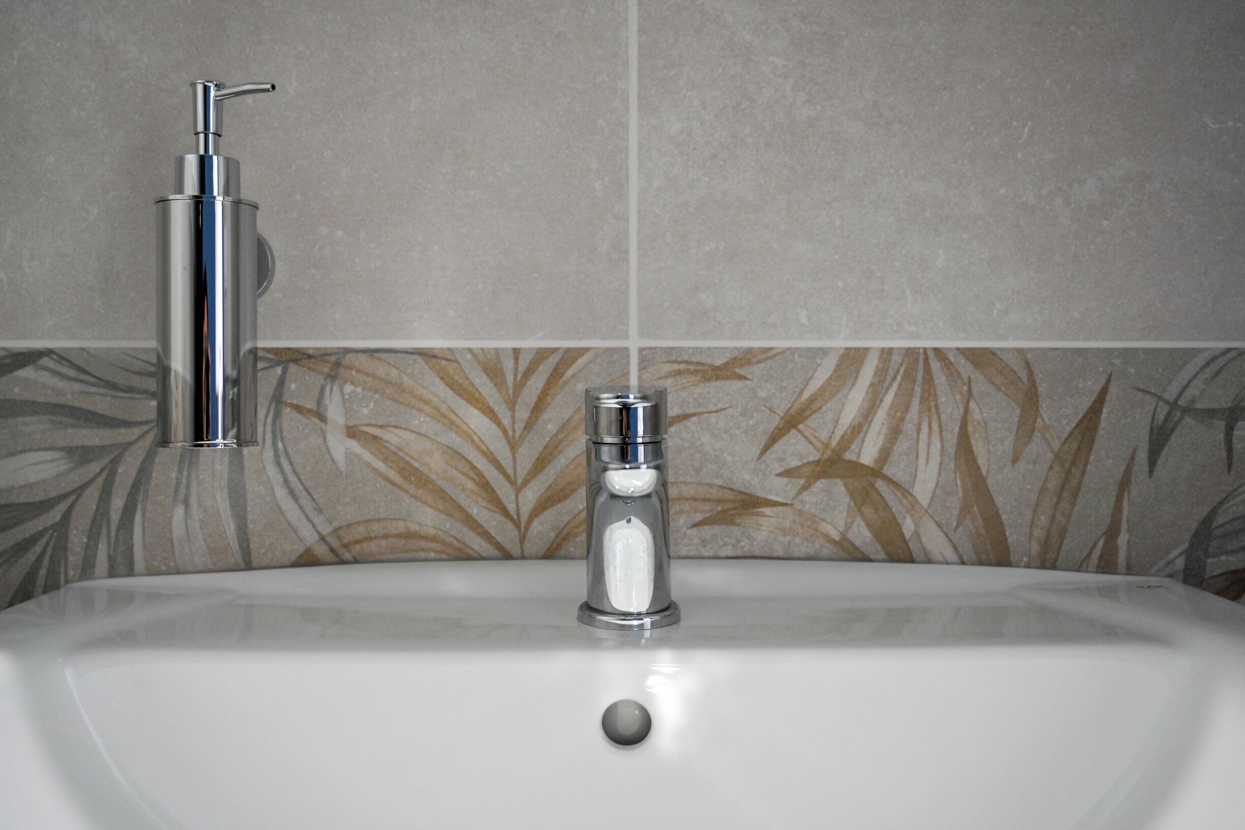 Ein Waschtisch mit einem modernen Wasserhahn und einer Seifenspender.