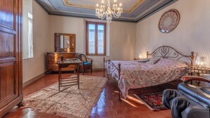A bedroom with a bed, a dresser, a chair, a desk, and a chandelier. - Orazio Liberty House, Lunigiana, Nature (Fivizzano)