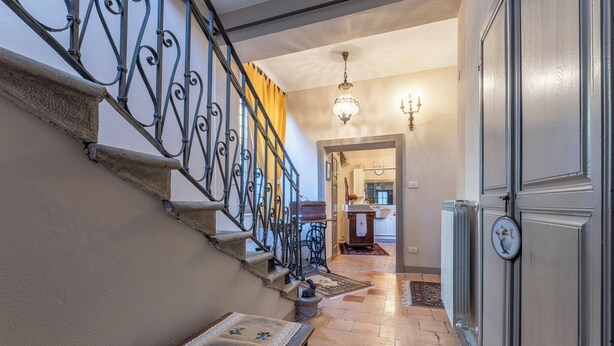 A staircase with ornate metal railings, a chandelier, and a patterned rug on the floor. - Orazio Liberty House, Lunigiana, Nature (Fivizzano)