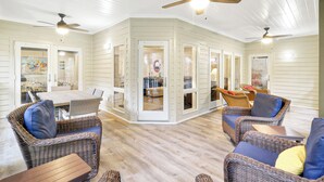A spacious indoor area with wicker furniture, ceiling fans, and a wooden floor. - Luxury Wendover Dunes villa, steps to ocean (Hilton Head Island)