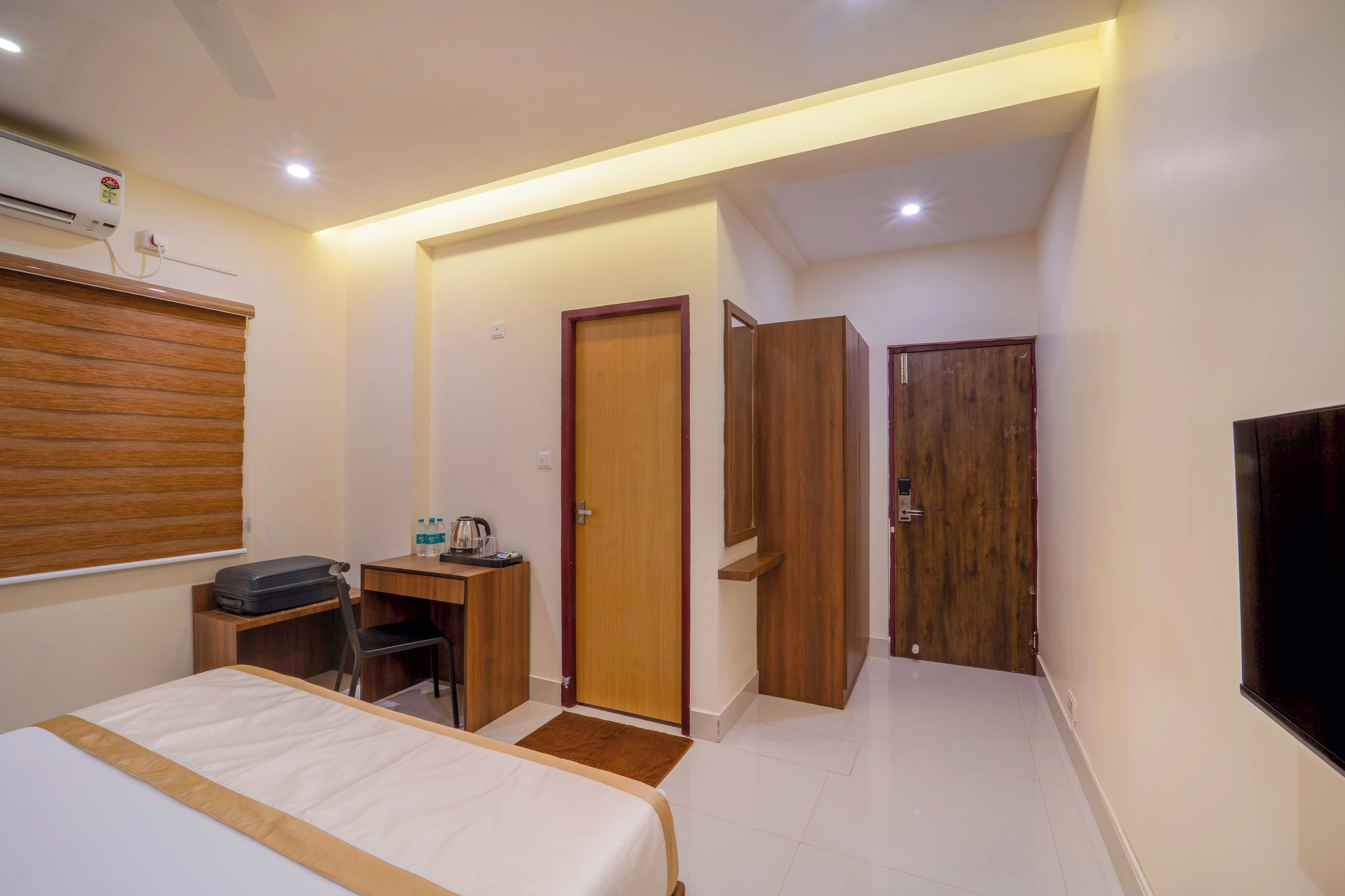 Una habitación de hotel con cama, escritorio, silla, armario y televisor.