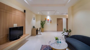 Un salon moderne avec un téléviseur à écran plat, un canapé, une table basse et une plante en pot.