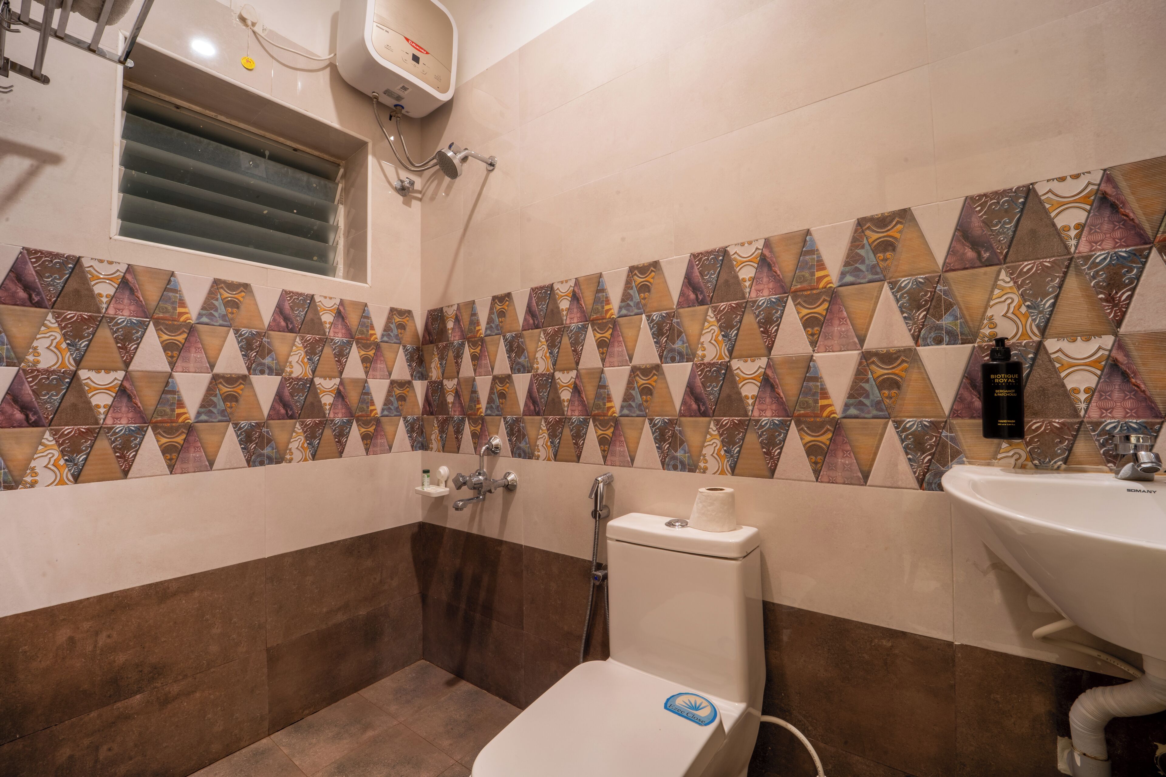 Un baño con baldosas estampadas, inodoro, lavabo y ducha.