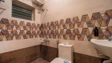 Un baño con baldosas estampadas, inodoro, lavabo y ducha.
