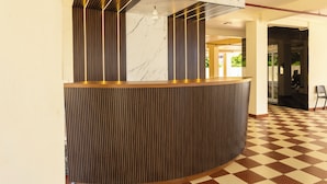 Un espace d’accueil doté d’un comptoir d’accueil incurvé, de lambris en bois verticaux et d’un sol à carreaux.