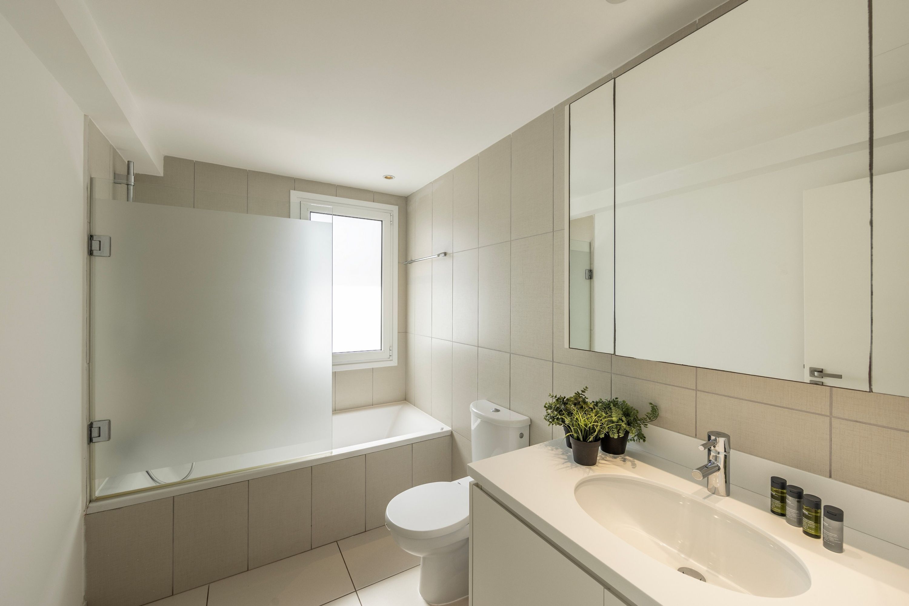 A modern bathroom with a bathtub, toilet, sink, and a large mirror.
