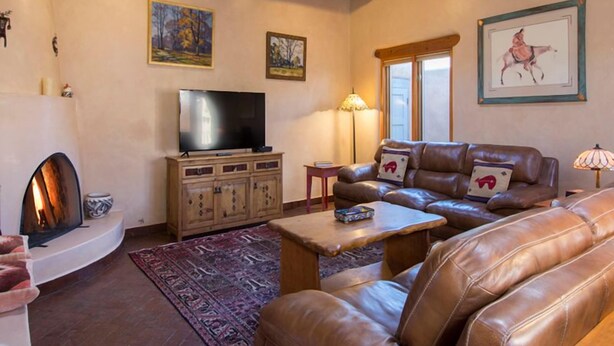Una sala de estar con chimenea, sofás de cuero, televisión y obras de arte en las paredes.