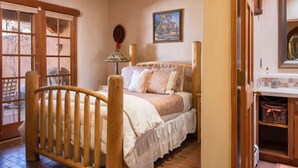 Un dormitorio con una cama de madera, una ventana, una puerta y un cuadro en la pared.
